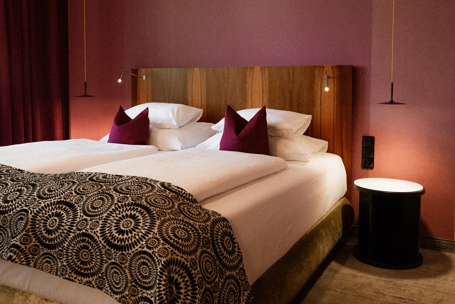 Doppelbett mit Dekokissen und stilvoller Beleuchtung in einem modernen Hotelzimmer